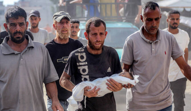 A man carries the body of Yahya Fadi al-Najjar, an infant who died due to malnourishment, during the funeral at Nasser Medical Complex in Khan Yunis in the southern Gaza Strip on July 20, 2025. (AFP)