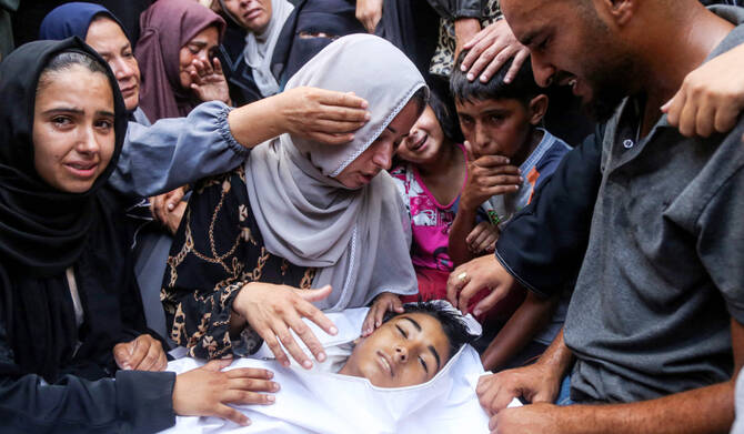 Mourners gather by the body of a young victim killed the previous day by Israeli bombardment during the funeral at Nasser Medical Complex in Khan Yunis in the southern Gaza Strip on July 20, 2025. (AFP)