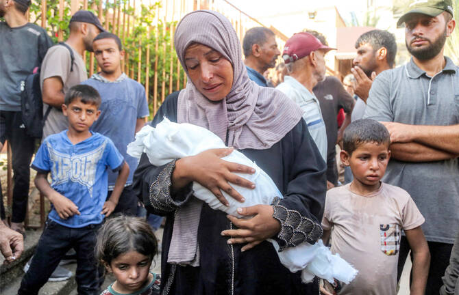 The mother of Yahya Fadi al-Najjar, an infant who died due to malnourishment, mourns as she holds his body during the funeral at Nasser Medical Complex in Khan Yunis in the southern Gaza Strip on July 20, 2025. (AFP)