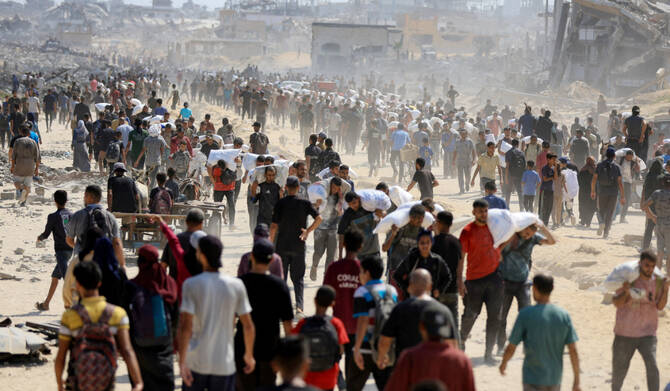 Palestinians gather as they carry aid supplies that entered Gaza through Israel, amid a hunger crisis, in Beit Lahia in the northern Gaza Strip July 20, 2025. (REUTERS)