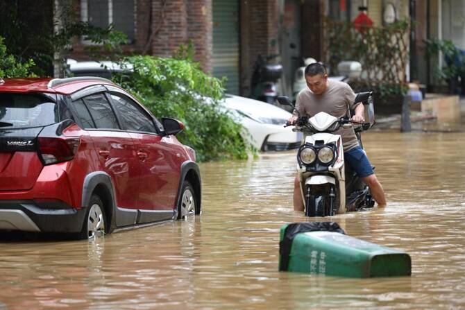 A file photo of a man rides through a flooded street in Zhongshan, in China's southern Guangdong province on June 17, 2025. (AFP)