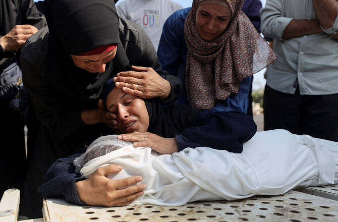 Mourners react next to the body of a Palestinian child killed in an Israeli strike, at Shifa hospital in Gaza City on July 22, 2025. (Reuters)