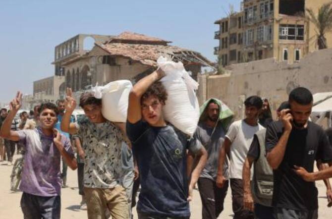 People make their way along Al-Rashid street in western Jabalia on July 22, 2025, after receiving humanitarian aid from an aid distribution point in the northern Gaza Strip. (AFP)