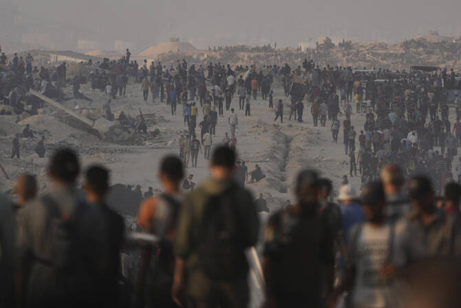 Palestinians walk along a road toward an area in the northern Gaza Strip where trucks are entering with humanitarian aid, in Gaza City, Friday, July 25, 2025. (AP)
