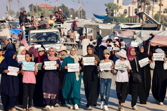 Women and children hold up signs as they attend a silent march against war and hunger in the Mawasi area in the east of Khan Yunis in the southern Gaza Strip on July 26, 2025. (AFP)