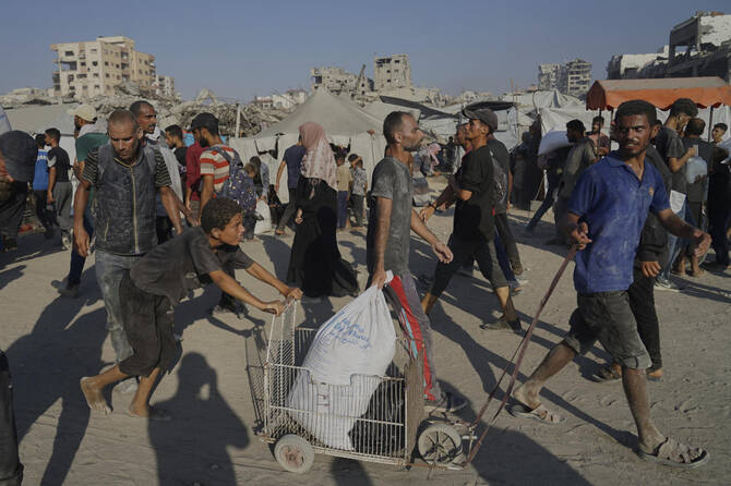 Palestinians carry sacks of flour unloaded from a humanitarian aid convoy that reached Gaza City from the northern Gaza Strip on July 26, 2025. (AP)
