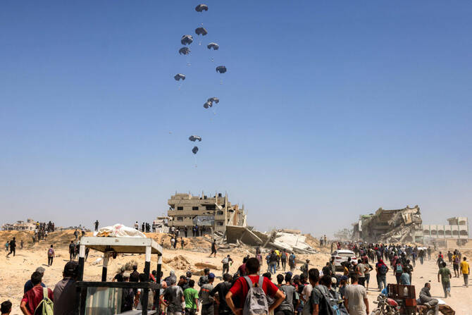 People gather as Jordanian and Emirati plane military transport aircraft drop humanitarian aid on the northern Gaza Strip on July 27, 2025. (AFP)