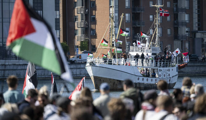 Demonstrators carrying Palestinian flags look on as the Ship to Gaza boat 'Handala' arrives at the port of Malmö, Sweden, Wednesday, May 8, 2024. (AP)