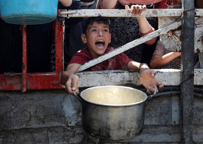 A Palestinian reacts as he waits to receive food from a charity kitchen, amid a hunger crisis, in Gaza City, July 28, 2025. (REUTERS)