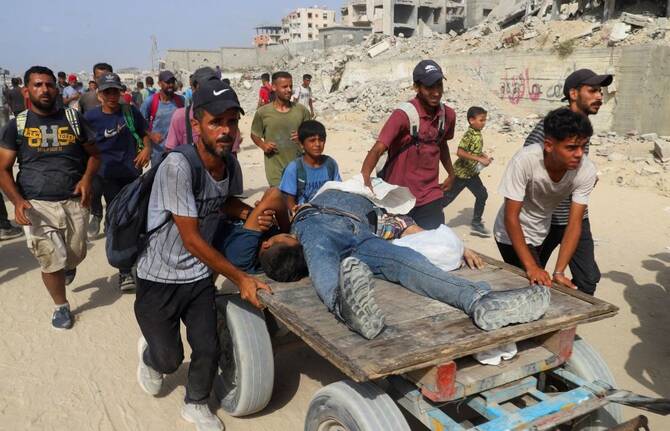 Palestinians wounded by Israeli fire are transported on a cart, as others carry aid supplies, Beit Lahia, northern Gaza Strip, July 29, 2025. (Reuters)
