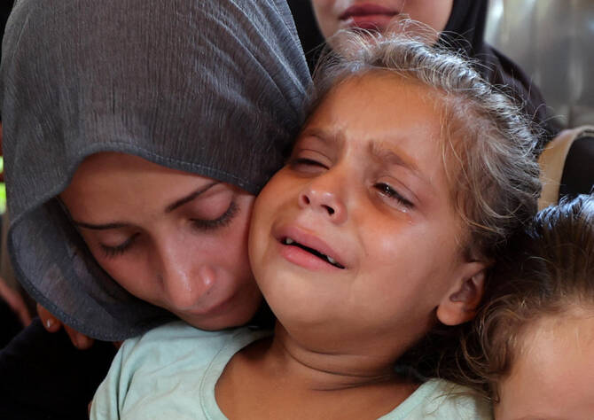 A woman and a child react during the funeral of Palestinians, who were killed by Israeli fire while trying to receive aid on Wednesday. (REUTERS)