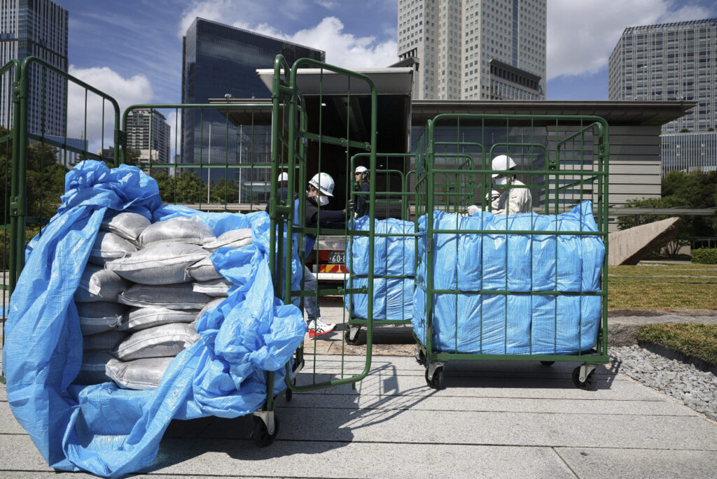 Workers unload bags of soil removed during decontamination following the Fukushima Daiichi nuclear power plant accident, at the Prime Minister's office in Tokyo on July 19, (AFP)