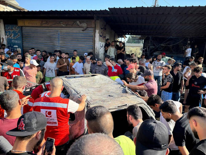 People gather near a damaged car after the Israeli military said in a statement that it struck a “key” figure from Hamas, in Ayrounieh, northern Lebanon July 8, 2025. (Reuters)