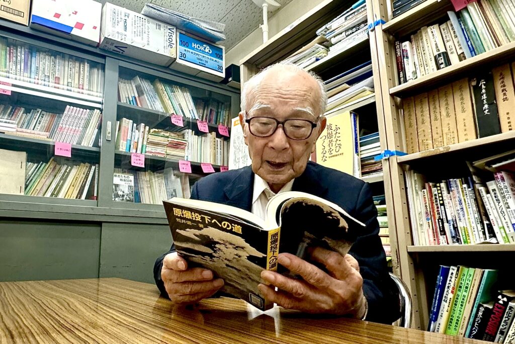 Nihon Hidankyo co-chair TANAKA Terumi viewing a book about the atomic bombing. (ANJ) 