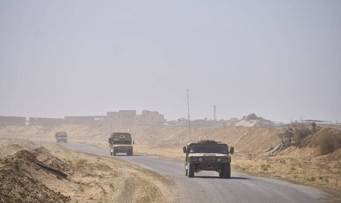 Israeli army vehicles transport a group of soldiers and journalists along the Morag corridor in southern Gaza. (AP)