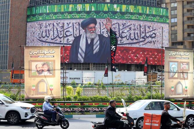 Motorists drive their vehicles past a billboard depicting Iran's Supreme Leader Ayatollah Ali Khamenei displayed in the centre of Tehran's Valiasr Square on July 13, 2025. (AFP)