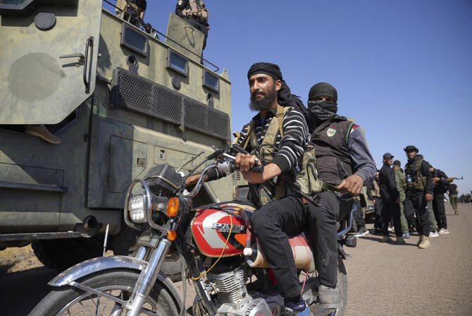 Two fighters from the Sunni Bedouin clans, ride their motorcycle as they pass by Syrian government security forces deployed on the outskirts of the Sweida province where clashes erupted between Druze militias and Sunni Bedouin clans, southern Syria, Monday, July 14, 2025. (AP)