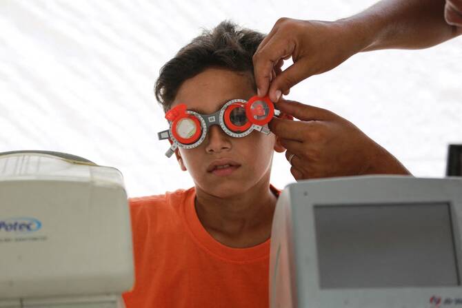 Palestinian ophthalmologist adjusts an interpupillary distance test frame as he checks the eyes of an internally displaced patient from Gaza City, June 27, 2024. (Agence France-Presse)