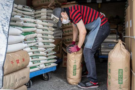 A member of staff works as bags of rice are seen piled up at a rice store in Tokyo on July 9, 2025. (AFP)
