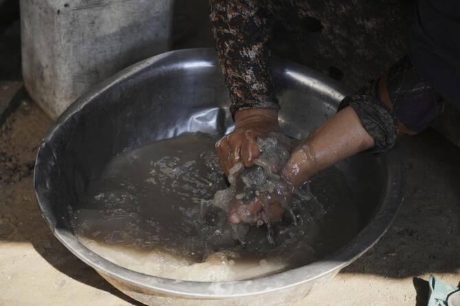 Abeer Sobh washes clothes inside her family's tent at a camp for displaced Palestinians in Gaza City on Thursday, July 24, 2025. (AP Photo/Jehad Alshrafi)