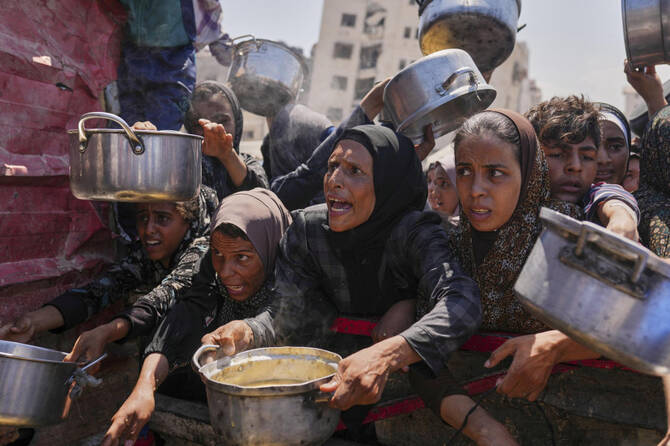 Palestinians struggle to get donated food at a community kitchen in Gaza City, northern Gaza Strip, Monday, Aug. 4, 2025. (AP)