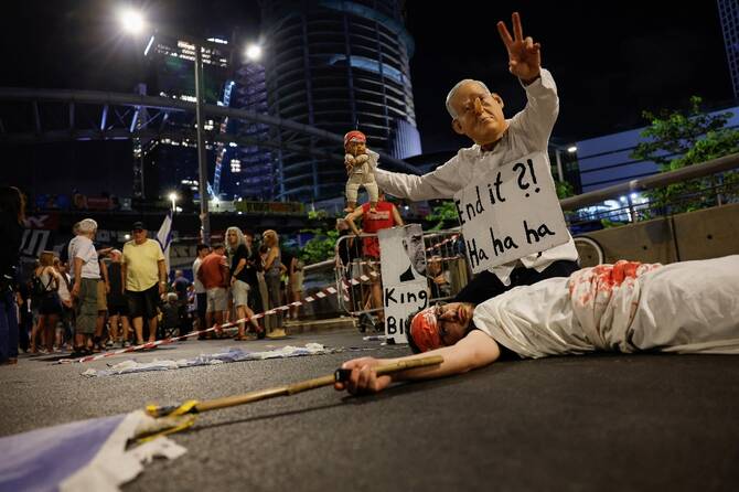 A demonstrator wearing a mask depicting Israeli Prime Minister Benjamin Netanyahu gestures, during a protest in Tel Aviv, Israel. (Reuters)