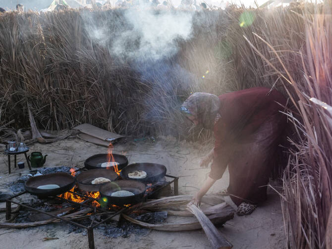 A Bedouin woman cooks traditional food in her encampment during the Sahara Festival in Douz, Tunisia, on December 22, 2018. (AFP)