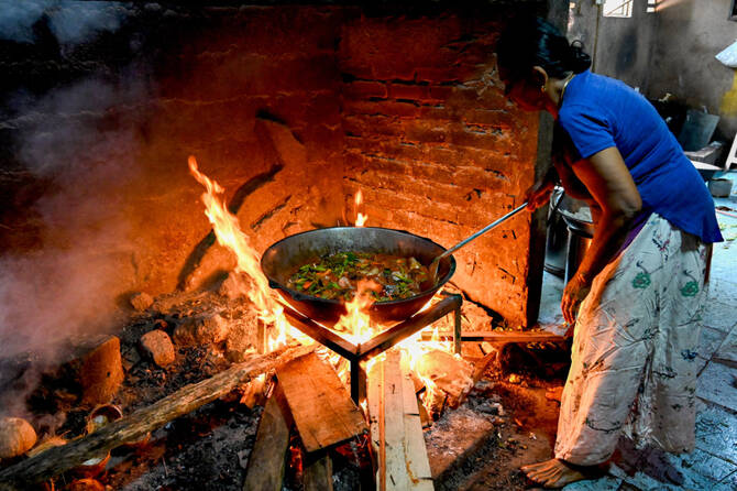 In this picture taken on March 15, 2022, a woman uses firewood to cook food at a hotel in Colombo. (AFP/File)