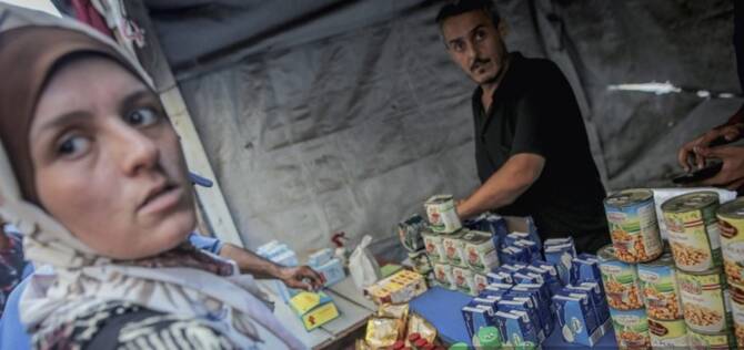 A woman stands at a stall that sells bottled drinks and canned foods in Gaza City. (AFP)