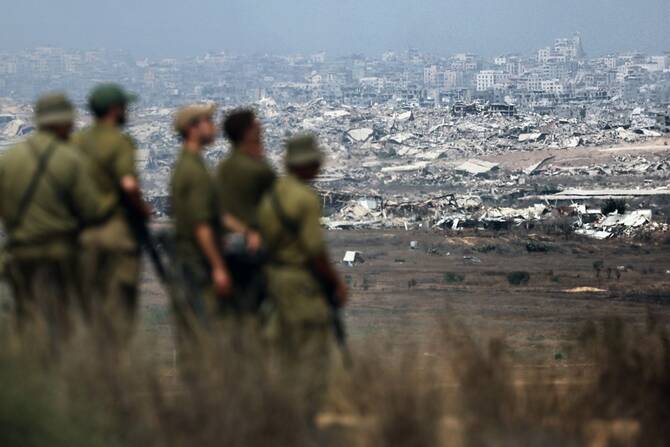 Israeli army soldiers look at destroyed buildings in the Gaza Strip as they stand on the border with the Palestinian territory, on August 13, 2025. (File/AFP)