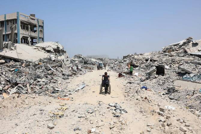A Palestinian boy pulls a wheelchair past destroyed buildings in the Al-Tuffah neighbourhood of Gaza City on Thursday. (AFP)