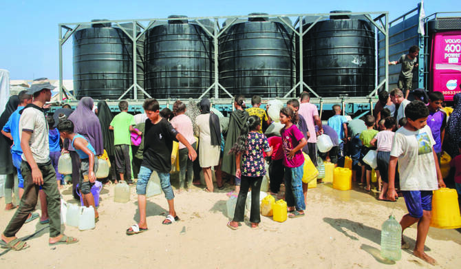 Displaced Palestinians attempt to fill water tanks in the Mawasi area of Khan Younis amid the worsening crisis and the spread of diseases. (AFP)