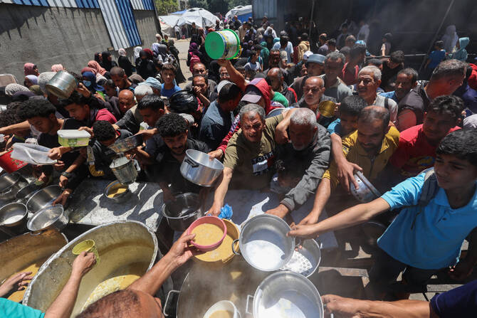 Palestinians queue for a hot meal at a charity kitchen run by the United Nation's World Food Programme (WFP) at the Nuseirat refugee camp in the central Gaza Strip on April 26, 2025.