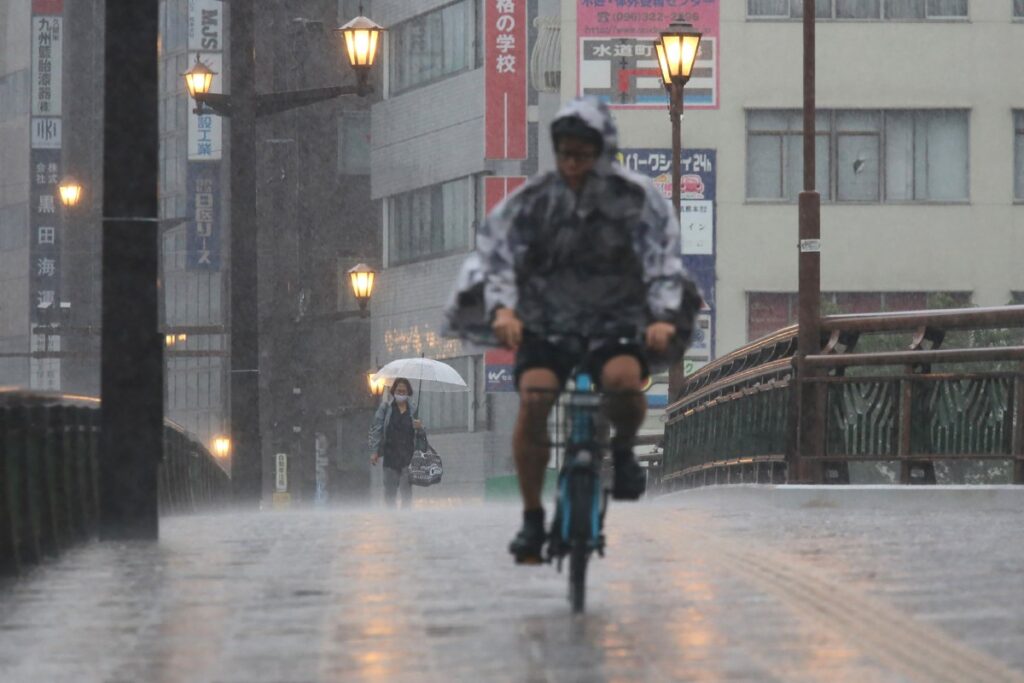 People cycle and walk in heavy rain in the city of Kumamoto, Kumamoto prefecture, southwestern Japan, on August 11, 2025. (AFP)