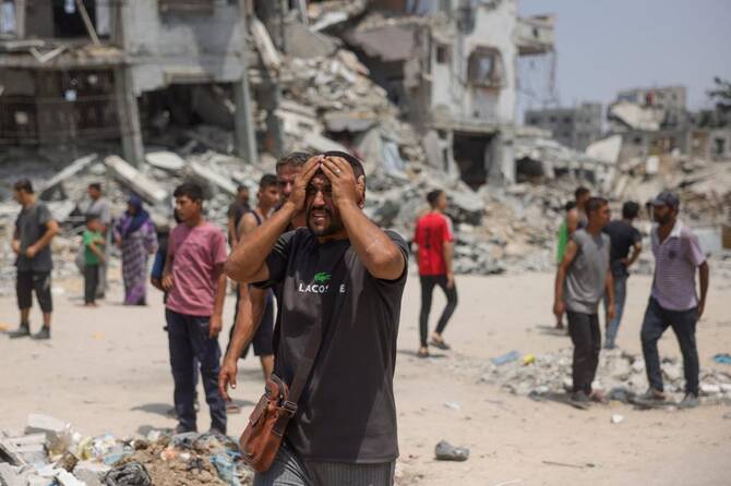 A man watches as medics transport casualties of Israeli strikes on members of aid security committees set up by volunteers from prominent Palestinian families to prevent aid theft, in the Saftawi neighborhood west of Jabalia in the northern Gaza Strip on Wednesday. (AFP)