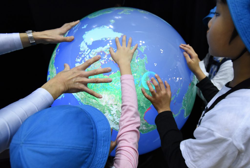 電子地球儀に触れて地球温暖化による海抜上昇について学ぶ生徒たち (AFP)