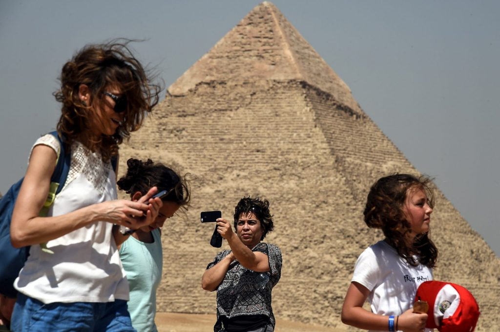 2019年5月29日、エジプトの首都カイロ南西のはずれにあるギザのピラミッド古墳群で携帯電話を手にポーズを取って「自撮り」する旅行者。（AFP）