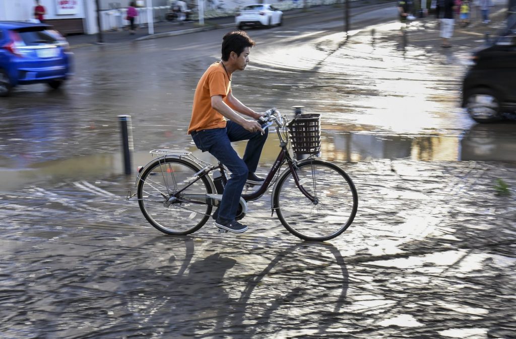 川崎市で台風ハギビスの余波の中、自転車をこいでいく男性 2019年10月31日。（ファイル写真/AFP）
