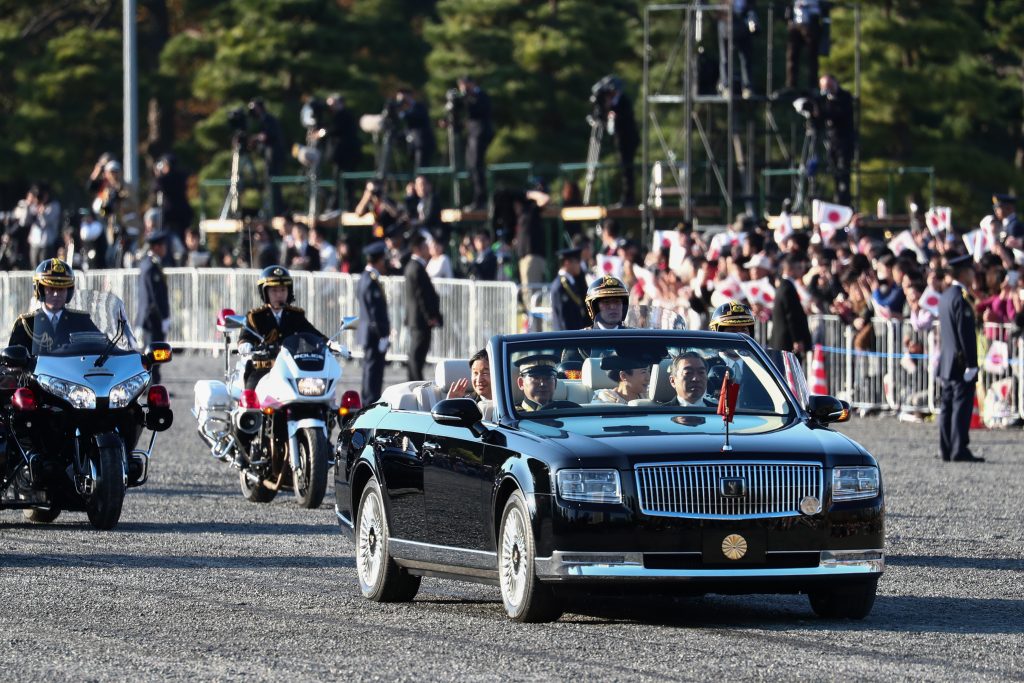 後方には秋篠宮ご夫妻らが乗った車が続き、皇居正門、国会正門前、国立国会図書館前、赤坂見附、青山通りを通って青山一丁目を右折する約４．６キロのコースを走り (AFP)