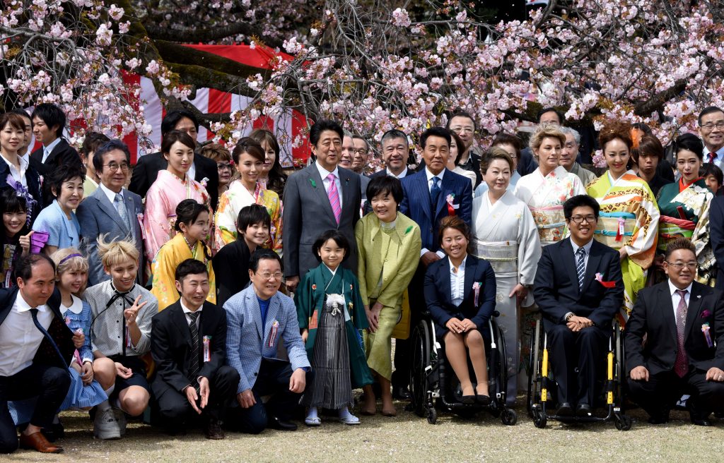 首相が東京で主催する桜を見る会で、芸能人やスポーツ選手とポーズをとる日本の安倍晋三首相(中央左)と昭恵夫人(中央右)。日本政府は2019年11月13日、安倍晋三首相が自身の後援者を招きすぎているという批判を受けた後、毎年恒例の桜を見る会を来年は中止すると発表した。(AFPファイル)