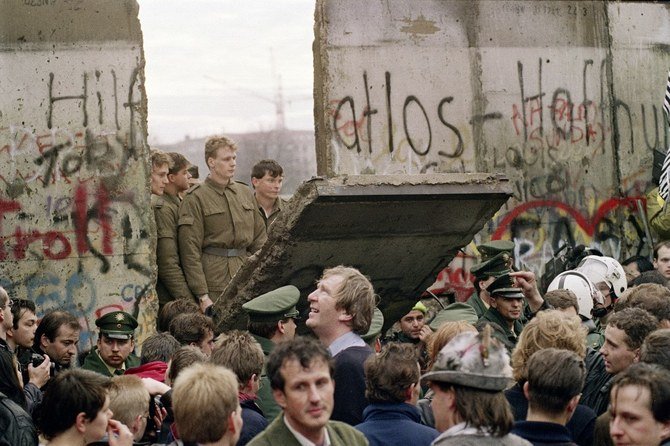 1989年11月11日朝、ベルリンの壁の前で、東ドイツの国境警備隊が東西間の通行場所を新たに開くために壁を一部撤去している様子を眺める西ベルリン市民の群衆。（AFP通信）