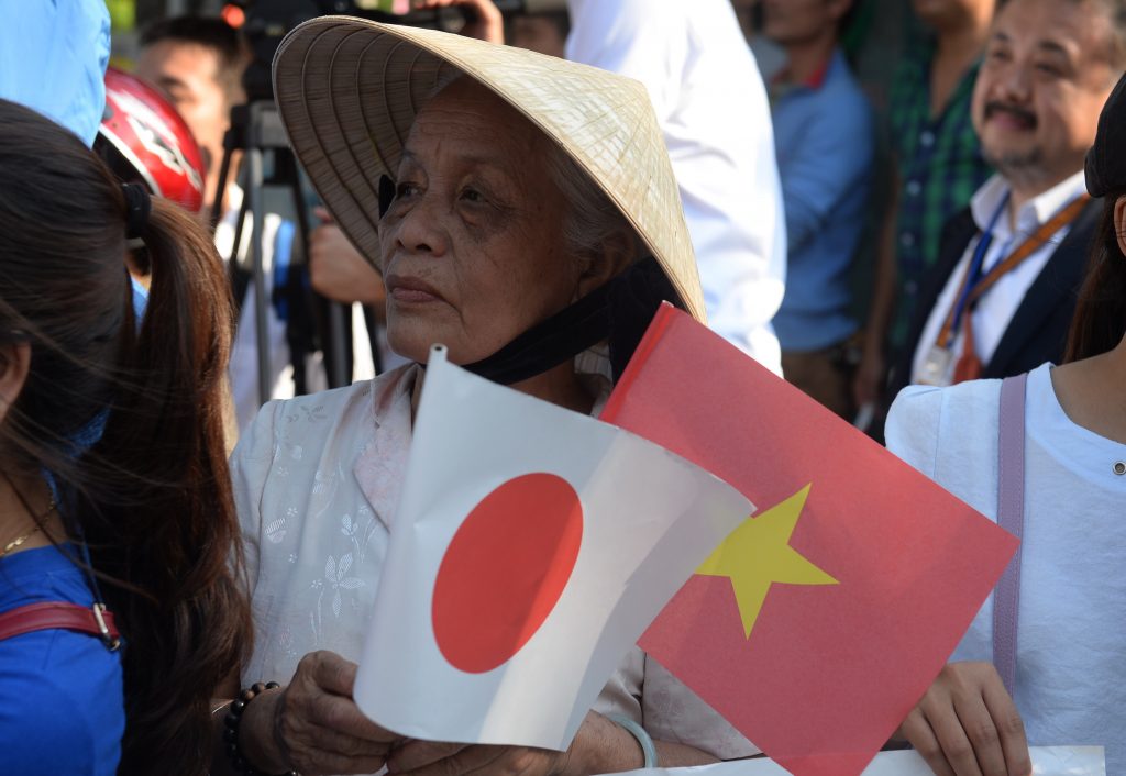 ベトナムと日本の旗を掲げるベトナム人の女性。国籍別に見ると、新たな特定技能で日本に居住している最多の国籍はベトナムであった。(AFPファイル