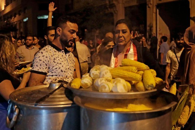 写真3：ベイルート中心街での反政府デモの最中に、露天商から軸付きのとうもろこしを買うレバノンのデモ参加者たち。（AFP）