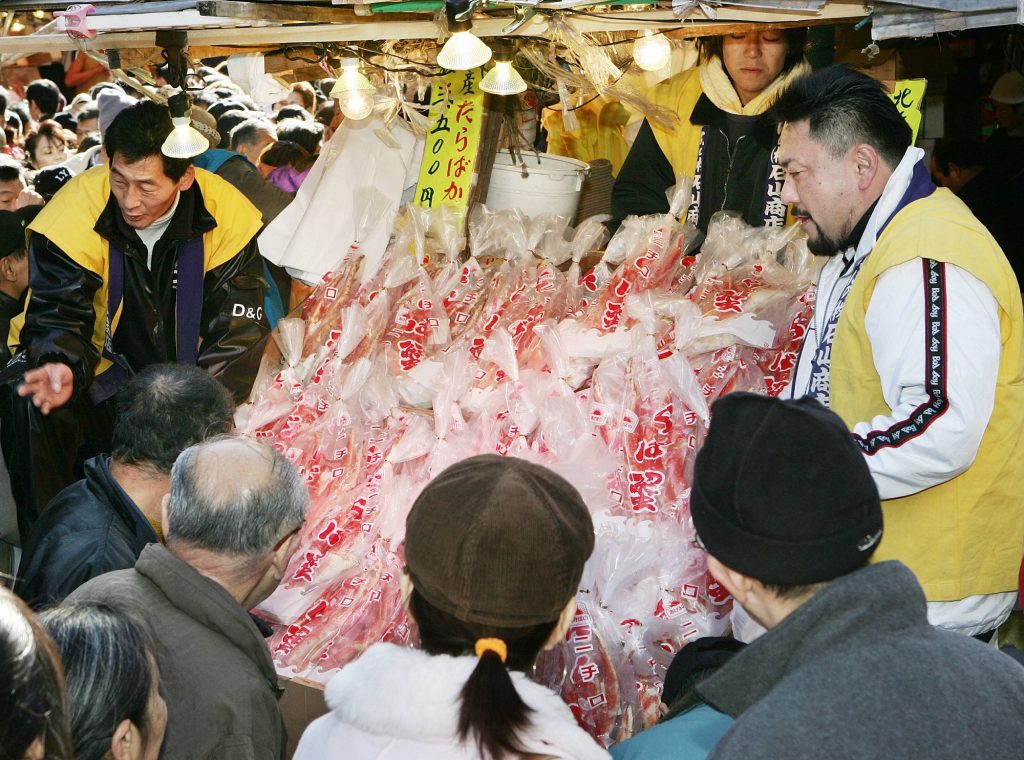 東京・上野のアメ横商店街のカニ屋で年末の買い物客と価格を交渉する魚屋（左および右）。2005年12月31日撮影。（ファイル写真/ AFP）