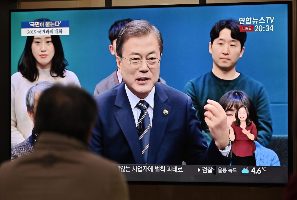2019年11月19日、ソウルの鉄道駅で、トークショーでの文在寅(C)韓国大統領のライブ映像を放送するテレビ画面を眺める男性。(AFP)