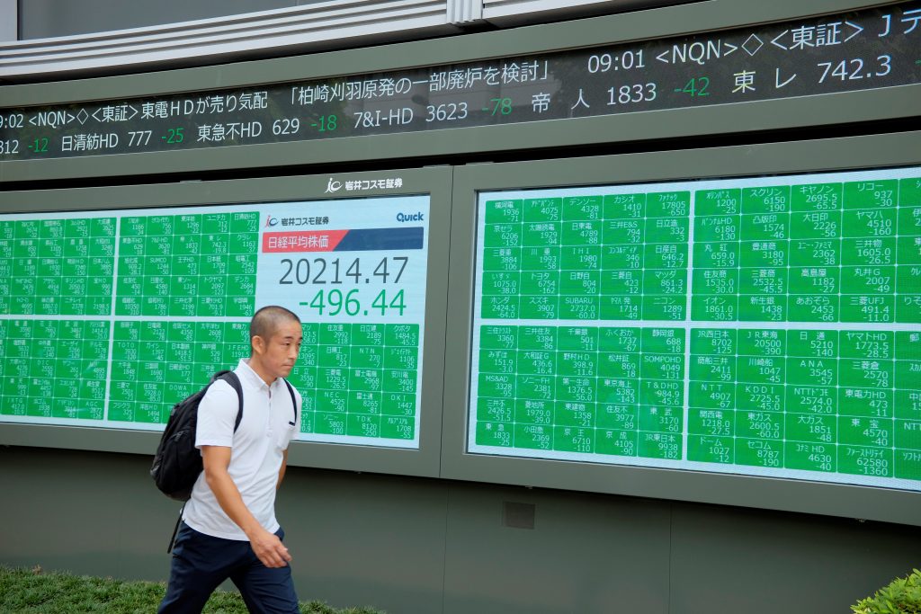 2019年9月26日、東京株式市場の日経平均株価を表示する電光相場表示板の前を横切る通行人。（AFP）