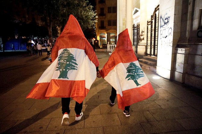レバノンのベイルート中心街で反政府の抵抗が行われている間に彼らが街路を歩いていたときの、レバノン国旗を身に着けたカップル。2019年11月2日（ロイター）