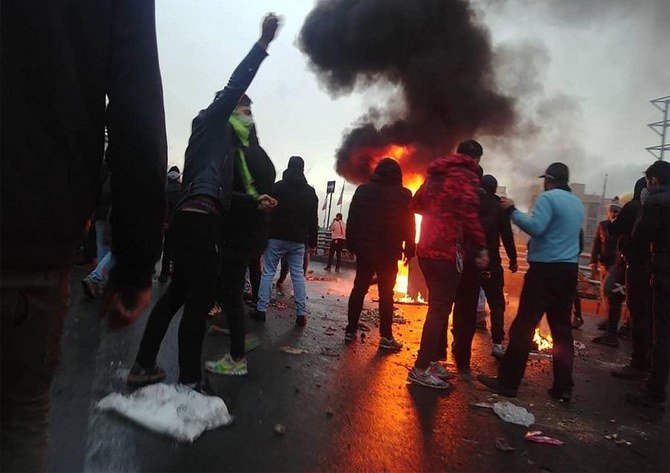 首都テヘランで、ガソリン価格の上昇に反対する抗議活動中に火の周りに集まるイランのデモ隊。2019年11月16日撮影（ファイル/ AFP）