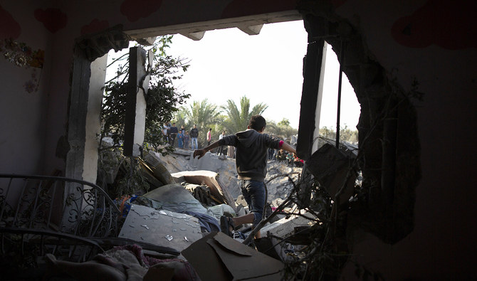 イスラエルの夜間ミサイル攻撃から一夜明けたガザ地区南部の都市ハーン・ユーニスで、破壊された家屋に開いた穴を通り抜けるパレスチナ人少年(AP)