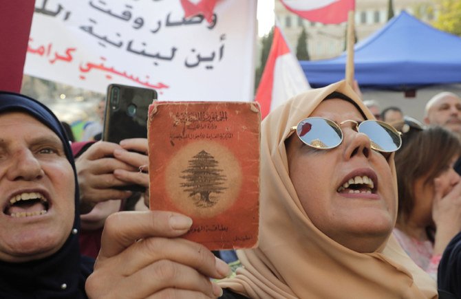 2019年11月10日、首都ベイルートの中心部で「私の国籍、私の尊厳」と記した、古い身分証明書を掲げるレバノン人のデモ参加者。レバノン人女性の子供に対し、レバノン国籍の取得を認めるよう要求している。（AFP通信 /アンワル・アムロ）